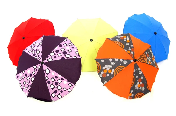 Five small colorful patterned umbrellas laid open on a white background, a mix of solid and patterned designs in warm, rustic tones.
